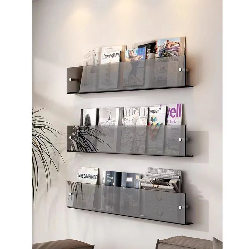 Three Avenue wall-mounted magazine shelves in smoked grey acrylic, holding magazines on a white wall.