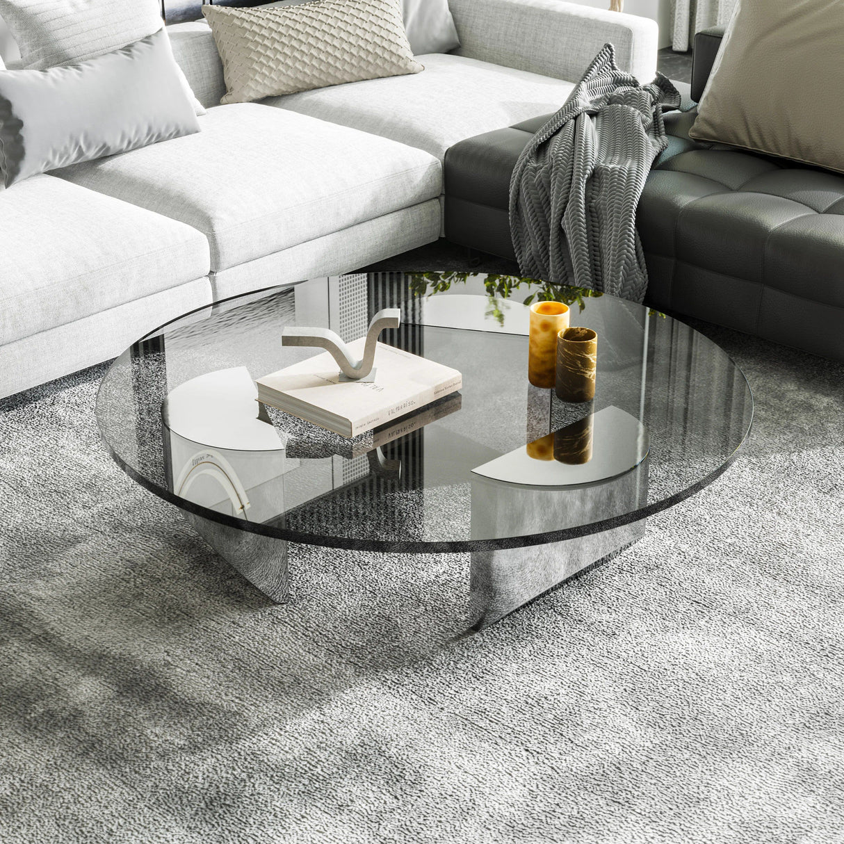Bassano round coffee table with clear glass top and chrome geometric base on a gray rug.
