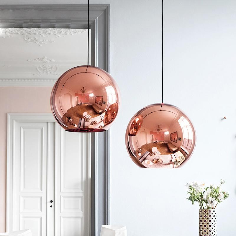 Two round, rose gold metallic Chroma pendant lights hanging in a modern room.