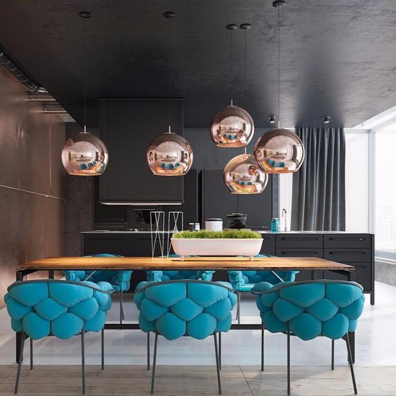 Five copper Chroma pendant lights hang above a long wooden dining table with blue upholstered chairs.