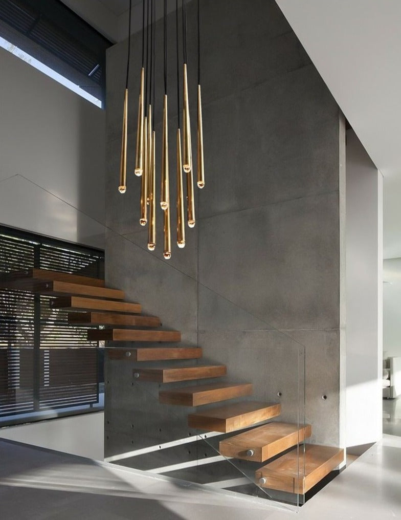 Evora pendant chandelier with multiple gold-finished conical lights hanging above a modern wooden staircase.