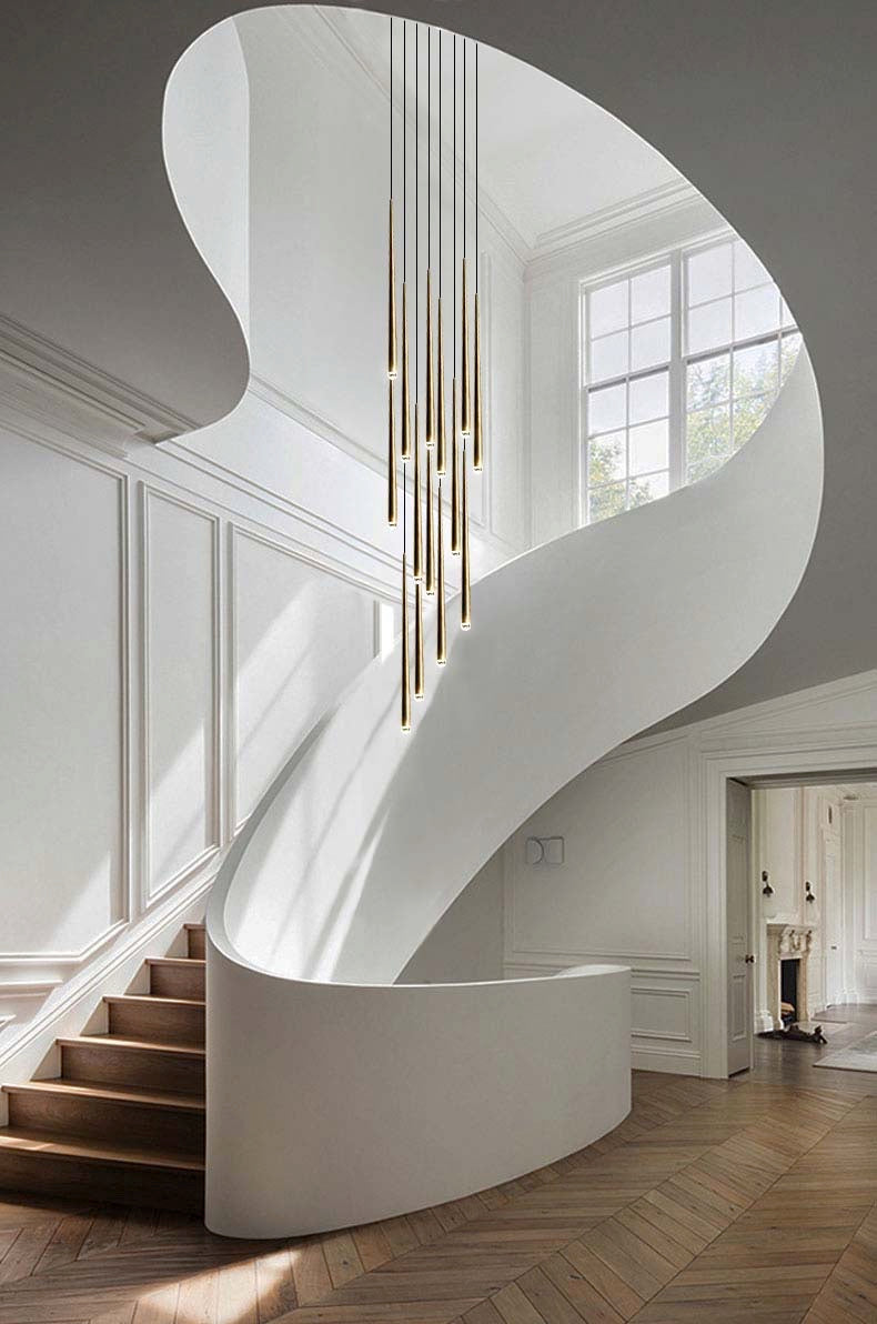 Evora pendant chandelier with multiple long, thin gold lights hanging in a modern white spiral staircase.