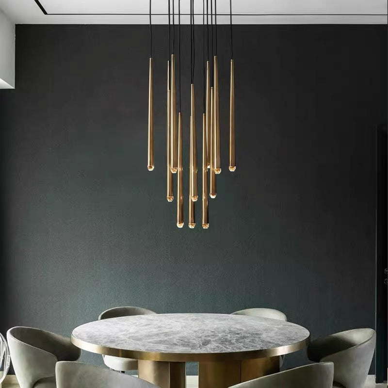 Evora gold modern pendant chandelier with multiple tubular lights over a gray marble dining table.