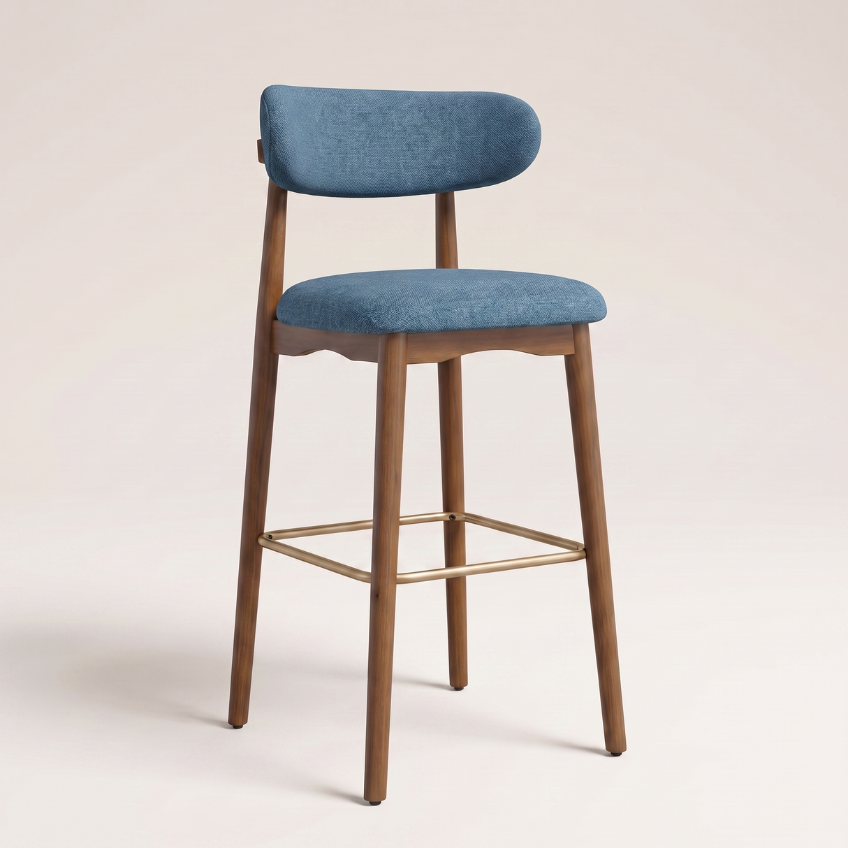 A modern bar stool with a blue upholstered seat and curved backrest, supported by a natural wood frame with a gold metal footrest, set against a solid light beige background.