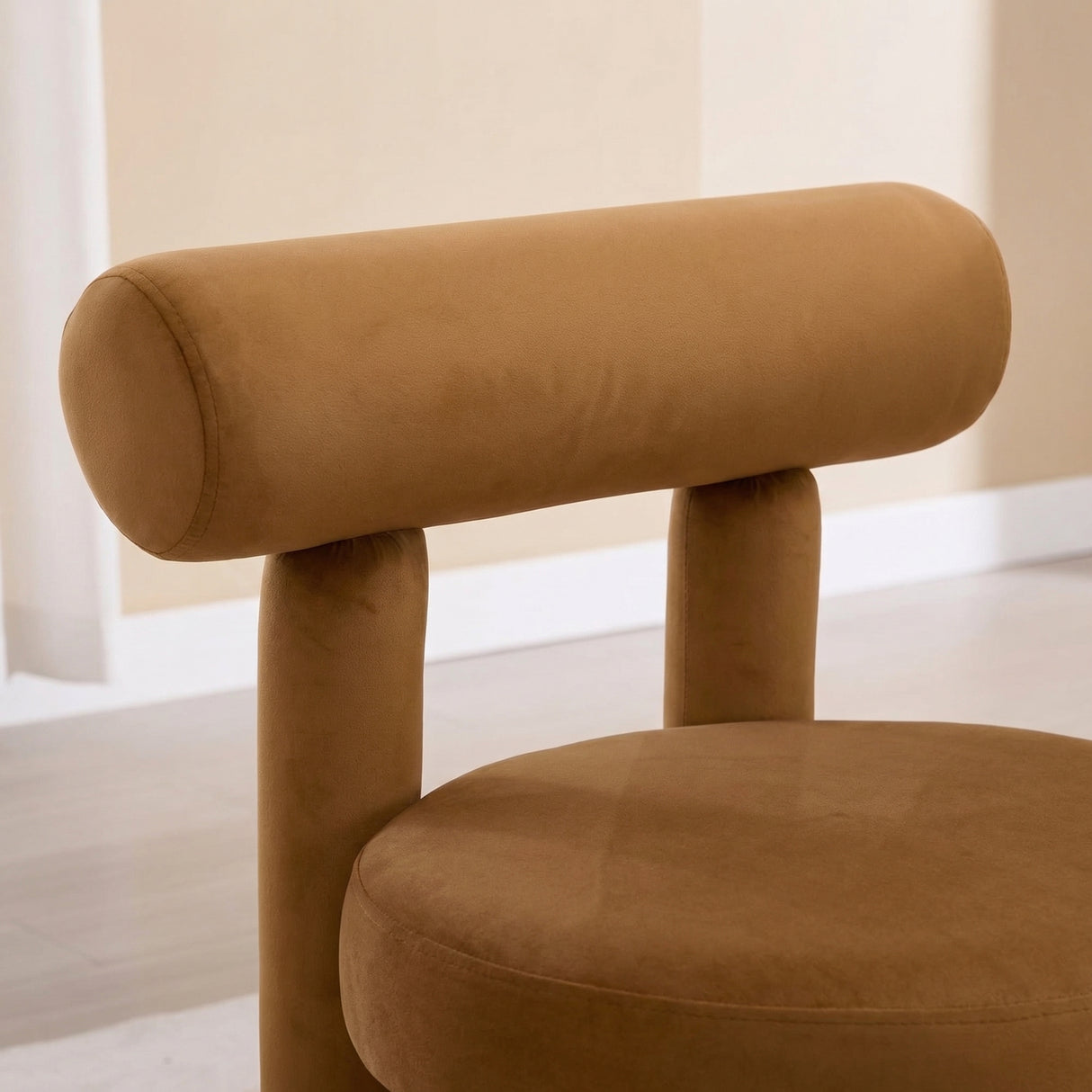 Rogolo Dining Chair with a round, camel-colored velvet seat and cylindrical backrest.