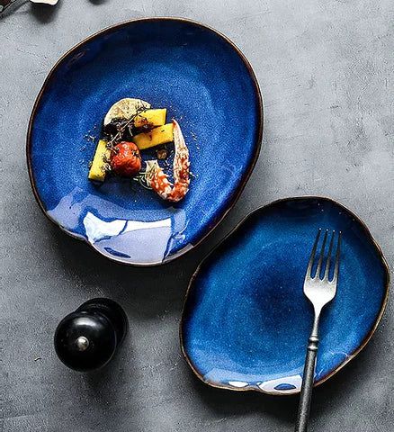 Atlas Dinner Plate: Two deep blue ceramic dinner plates with irregular edges and a brown rim.