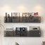 Avenue wall-mounted magazine shelf in smoke acrylic, holding magazines on a white wall.