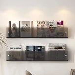 Avenue wall-mounted magazine shelf in smoke acrylic, holding magazines on a white wall.