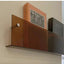 Avenue wall-mounted magazine shelf in tea-colored acrylic, 30cm, holding books on a beige wall.