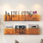 Orange acrylic wall-mounted magazine shelf, 30cm, holding magazines on a white wall.