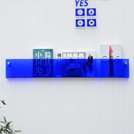 Blue acrylic Avenue Wall-Mounted Magazine Shelf, 30cm, holding books and magazines on a white wall.