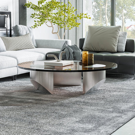 Bassano coffee table with a round dark glass top and light silver curved base in a modern living room.
