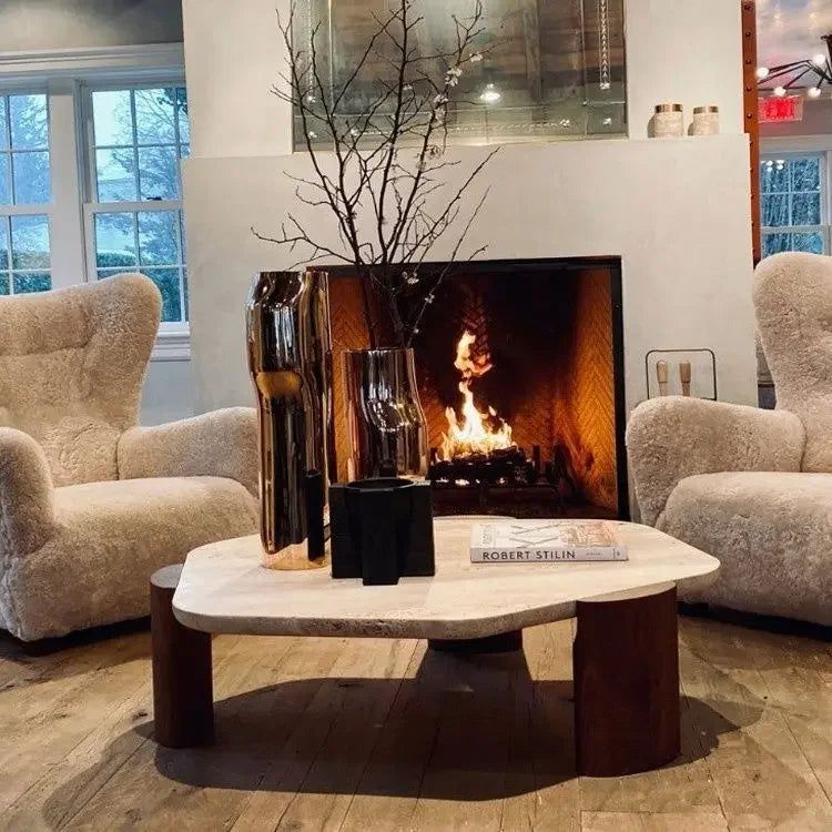 Borra coffee table with a light stone top and dark wood log legs in a living room setting.