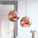 Two round, rose gold metallic Chroma pendant lights hanging in a modern room.