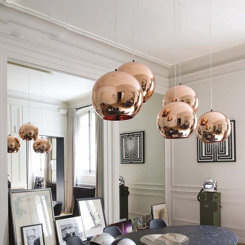 Rose gold Chroma pendant lights with a mirrored finish hanging in a modern dining room.