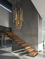 Evora pendant chandelier with multiple gold-finished conical lights hanging above a modern wooden staircase.