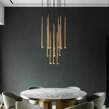 Evora gold modern pendant chandelier with multiple tubular lights over a gray marble dining table.
