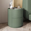 Mira Bedside Table in avocado green with two drawers and a round top, on a light wood floor.