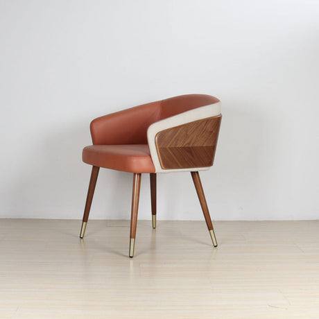 Modenal Dining Chair in orange leather with beige trim, wood paneling, and gold-capped tapered legs.