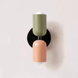 Mura Wall Light, a modern wall sconce with a green and peach cylindrical design on a black base.