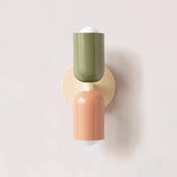 Mura Wall Light, Style 3. Modern wall sconce with stacked green and peach cylindrical shades on a cream base.