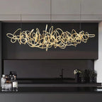 Parcaso Chandelier, 80cm gold abstract linear chandelier with warm white light over a black kitchen island.