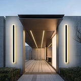 Spire Outdoor Wall Light: Two tall, black modern wall sconces with warm LED glow on a gray building exterior.