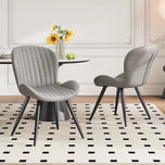 Lorca Dining Chair in light gray fabric with vertical channel tufting and black tapered legs, on a rug.