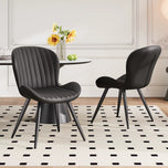 Lorca dining chair in black faux leather with vertical channel tufting and black tapered legs.