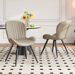 Lorca Dining Chair in beige fabric with vertical channel tufting and black tapered legs, shown in a dining room.