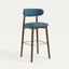Norden Bar Stool in denim blue fabric with a dark wood frame and brass footrest.