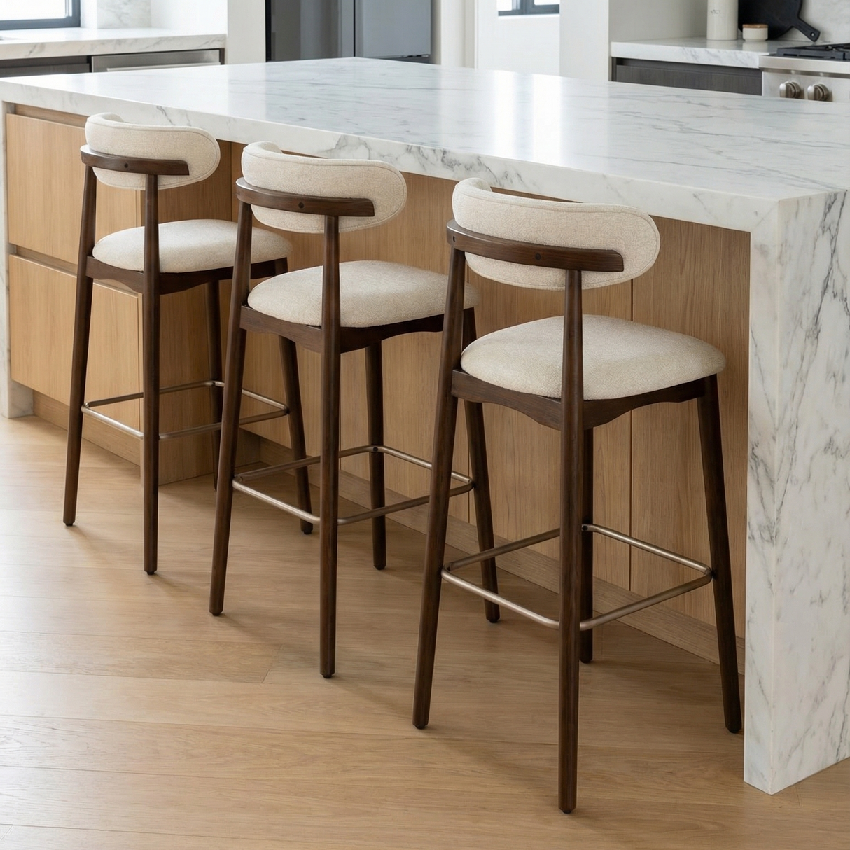Three Norden Bar Stools with dark wood frames, light fabric seats, and curved backs at a kitchen island.
