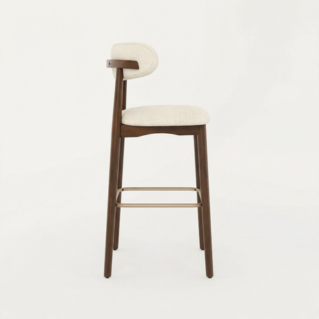 Norden Bar Stool with dark wood frame, light fabric upholstered seat and back, and brass footrest.