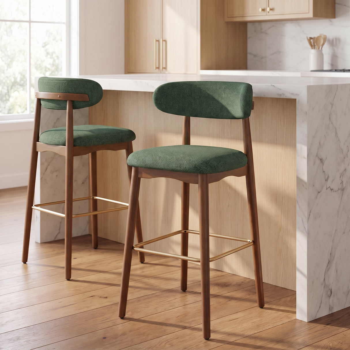 Two wooden bar stools with green upholstered seats and backs, placed at a kitchen island in a bright, modern kitchen.
