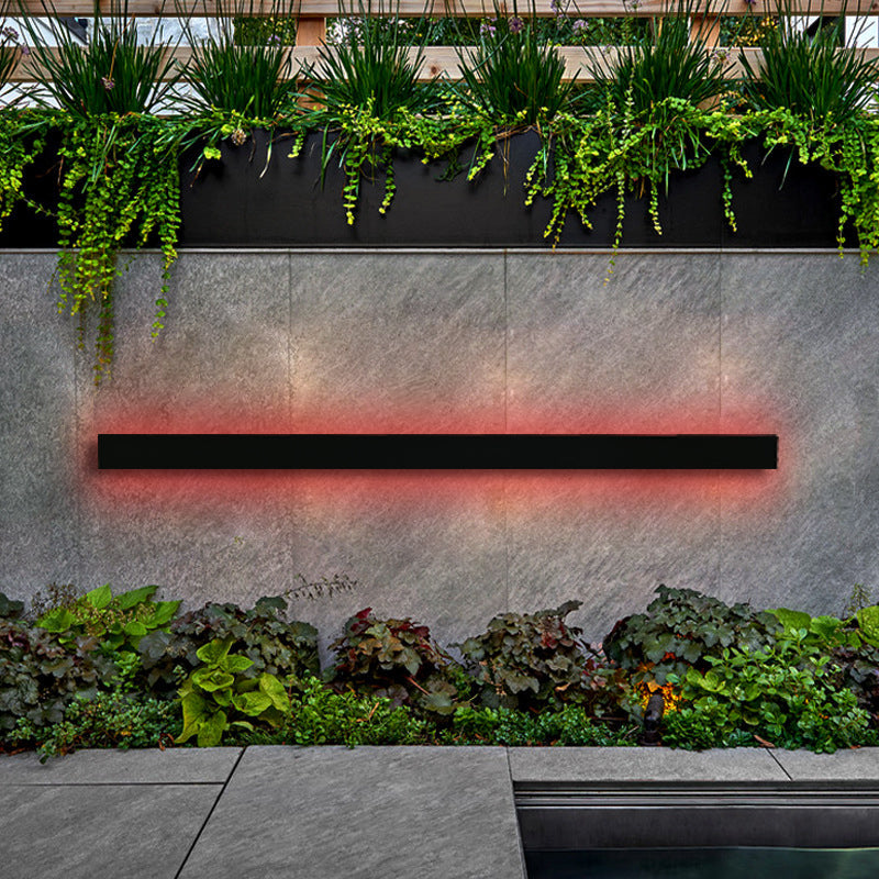 Parc Sconce outdoor wall light, a black linear fixture emitting a red RGB glow on a gray stone wall.
