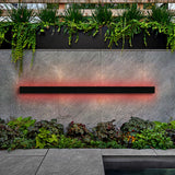 Parc Sconce outdoor wall light, a black linear fixture emitting a red RGB glow on a gray stone wall.