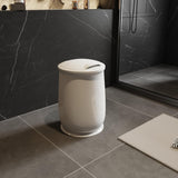 White towel warming bucket with a lid, on a dark tiled bathroom floor.