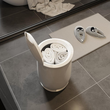 White towel warming bucket with three rolled towels, open lid, on a dark tiled bathroom floor.