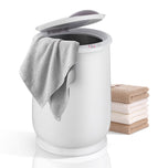White Parc Towel Warming Bucket with an open lid, a gray towel draped over the edge, and a stack of folded towels.