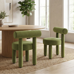 Rogolo Dining Chair in olive green velvet with cylindrical backrest and legs, beside a wooden dining table.