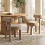 Rogolo dining chair in sand fabric, with a round seat and backrest, and thick cylindrical legs.