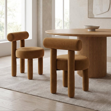 Rogolo dining chair in rust velvet with rounded back and legs, next to a matching chair and wood table.