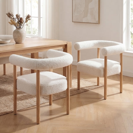 Sarlo Dining Chair in white boucle with light wood legs and curved backrest, shown in a dining room.